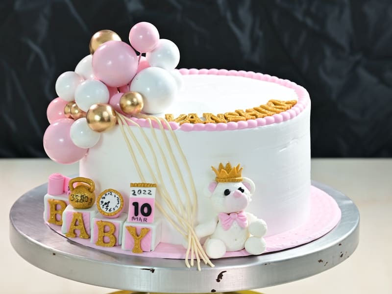 Baby shower cake with pastel balloons and a teddy topper at The Bakest, Okhla