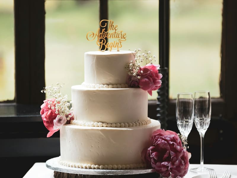 Three-tier white wedding cake with fresh flowers, custom baked at The Bakest, Okhla